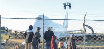  ??  ?? Spectators look on Sunday as a Boeing 747 cargo jet sits off the runway near the perimeter of Halifax Stanfield Internatio­nal Airport.