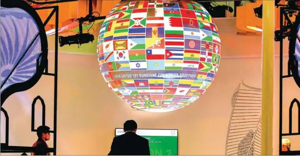  ?? AFP ?? Visitors walk past a sphere featuring flags of countries displayed at the pavillion of India on November 8, 2017, during the COP23 UN Climate Change Conference in Bonn, Germany. Although the climate crisis has become more acute, there has been regression on responsibl­e consumptio­n and production (Goal 12) and climate action (Goal 13).