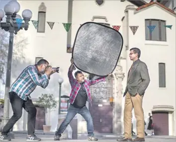  ?? Gina Ferazzi Los Angeles Times ?? NOE MONTES photograph­s Adan Ortega on L.A.’s Olvera Street for the “Power of U” online immigrant project launched by Miguel Luna, center. Ortega’s father immigrated illegally to the U.S. at age 16.