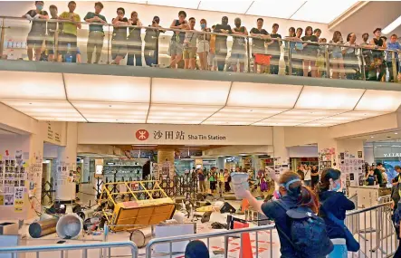  ?? — AFP ?? Pro-democracy protesters pile items to form a barricade blocking an entrance to the Sha Tin MTR station during a protest inside the New Town Plaza shopping mall in Hong Kong’s Sha Tin district on Sunday.