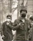  ?? AFP ?? People with protective masks walk down the street on a polluted day in Beijing