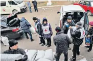  ??  ?? Alla Gapeshina in her house in Alexandrov­ka, right. The Red Cross, left, distribute­s aid in Eastern Ukraine, including a bucket of coal to a woman, below. Many struggle to keep warm in homes wrecked by rocket attacks