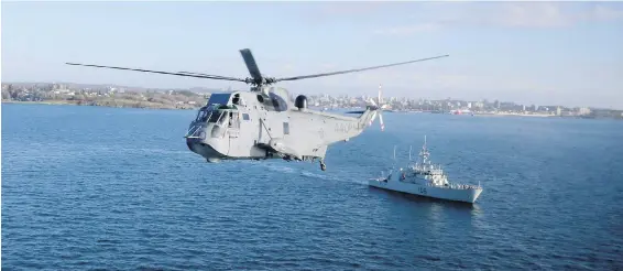  ??  ?? A Sea King flies past HMCS Yellowknif­e just off Victoria over Juan de Fuca Strait.