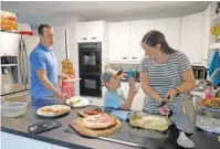  ?? AP PHOTO/AL GOLDIS ?? Chris and Kristen Umphlett prepare dinner with two of their four children, Kyria, 9, rear, and Derek 7, on June 30 in their home in East Lansing, Mich. The Umphletts have fostered unaccompan­ied migrant children during the pandemic.