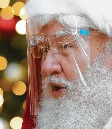  ?? Jason Fochtman / Houston Chronicle ?? Además de cubrir el rostro de Santa Claus y sus ayudantes con una máscara de plástico, la gente debe mantener distanciam­iento social para saludarlo con los niños en esta Navidad en TheWoodlan­ds Mall.