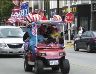  ?? WDN photo ?? A golf cart covered in patriotic regalia and toting a Trump 2020 flag makes its way down East Auglaize Street in Wapakoneta on Saturday.