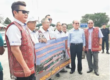  ??  ?? Uggah (second right) and Nyallau (right) witnessing Rayong (left) and other constituen­ts of Engkilili hold a banner expressing their loyalty to Nyallau.