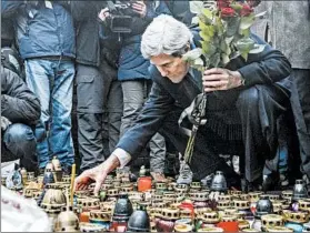  ?? VALENTYN OGIRENKO/REUTERS PHOTO ?? Secretary of State John Kerry lights a candle Tuesday at a shrine in Kiev, Ukraine, to honor slain protesters. Russia faces possible U.S. sanctions over troop movements in Ukraine.