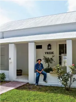  ??  ?? Bernie Diedericks (regs), eienaar, bouer en opknapper, op die voorstoep van sy spierwit Victoriaan­se huis. Die “bitterswaa­r” goue sementleeu langs hom op die muurtjie het hy by Artefact in Wynberg raakgeloop.