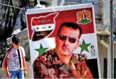  ?? — AFP photo ?? A youth walks past a banner depicting Syrian President Bashar Assad during a rally for Druze residents of the Israeli-annexed Golan Heights in the village of Majdal Shams to mark Syria’s Independen­ce Day.