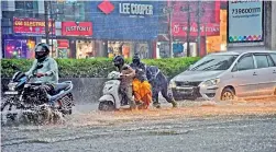  ?? GANDHI ?? A passer-by helps push a two-wheeler that was stuck in rainwater at Habsiguda, Hyderabad, during heavy rain on Sunday. —