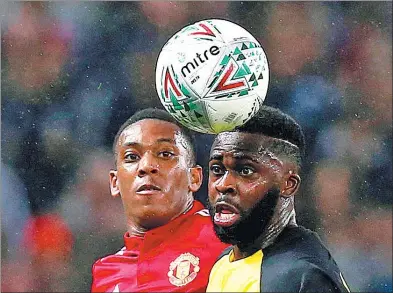  ?? ANDREW YATES / REUTERS ?? Manchester United's Anthony Martial is beaten to a header by Burton Albion's Hope Akpan during their English League Cup thirdround match at Old Trafford on Wednesday. United cruised past the Brewers 4-1.