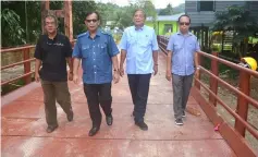  ??  ?? (From left) Abang Hamzah, Jamit, Sia and Edward walk across the almost completed bridge.