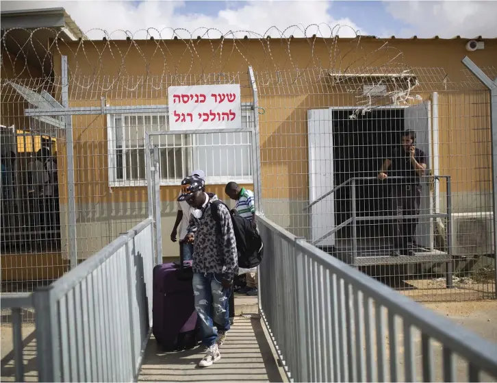  ??  ?? AFRICAN MIGRANTS walk with their luggage as they leave Holot detention center in the Negev in 2015.