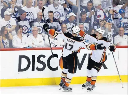  ?? Trevor Hagan Associated Press ?? THE OTHER SIDE OF THE GLASS is a cold and quiet place as Ryan Kesler and Jakob Silfverber­g celebrate in front of stunned Winnipeg fans after Kesler’s goal tied it for the Ducks with 2:14 left in third period. Rickard Rakell scored game-winner in...