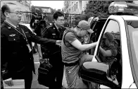  ?? FAN JUN / XINHUA ?? A fugitive suspected of theft from the United States is escorted to a police vehicle from a detention facility in Shanghai on Tuesday. He was later handed over to US law enforcemen­t officials.