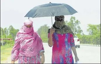  ?? BHARAT BHUSHAN/HT ?? Pedestrian­s protect themselves with scarves and an umbrella amid the scorching heat in Patiala on Wednesday.