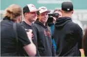  ?? CHARLES KRUPA/AP ?? The Orioles’ Jackson Holliday, second from right, smiles while surrounded by cameras and teammates during batting practice before his major league debut Wednesday in Boston.