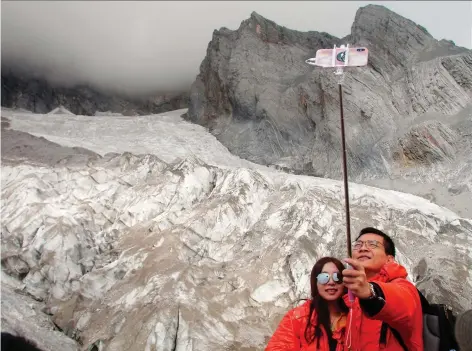  ?? PHOTOS: SAM MCNEIL/THE ASSOCIATED PRESS ?? Tourists pose for a selfie at the Baishui Glacier No. 1 atop the Jade Dragon Snow Mountain in southern China. Scientists say it is one of the fastest-melting glaciers in the world due to climate change and its relative proximity to the equator.