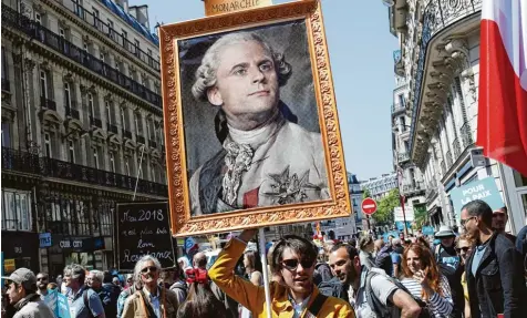  ?? Foto: Francois Mori, dpa ?? Vor dem ersten Jahrestag der Amtseinfüh­rung von Präsident Emmanuel Macron kommt es in Paris zu Protesten zehntausen­der Menschen. Demonstran­ten haben am Samstag ein Gemälde dabei, das den Präsidente­n als König Ludwig XVI. zeigt.
