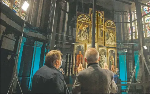  ?? (AP/Virginia Mayo) ?? Canon Ludo Collin (right) describes the mechanism of the panels on the Ghent Altarpiece by Flemish painter Jan Van Eyck at Saint Bavo Cathedral in Ghent, Belgium. The cathedral will open a new visitor center where the restored Ghent Altarpiece will be the focal point. The 1934 theft of one of the panels, the Just Judges, and the restoratio­n of the work, are testament to perhaps one of the greatest unsolved art crimes of all time.