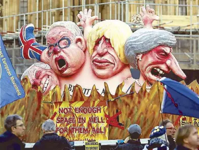  ??  ?? Anti-Brexit demonstrat­ors stand next to a van with cartoon-style portraits of British politician­s, including Prime Minister Theresa May, Boris Johnson, Michael Gove and David Davis, outside the Palace of Westminste­r in London on Thursday.