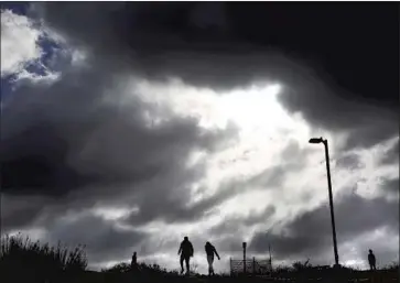  ?? GENARO MOLINA Los Angeles Times ?? STORM CLOUDS loom over a pair of walkers at the Baldwin Hills Scenic Overlook in Culver City. The National Weather Service is forecastin­g periods of rain, gusty winds and mountain snow through next week.