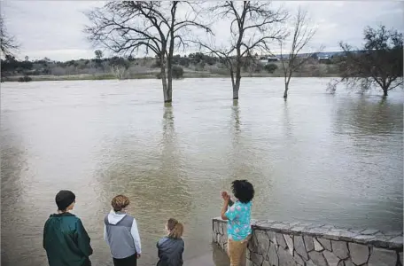  ?? Marcus Yam Los Angeles Times ?? FROM LEFT, Johnny Eroh, Cody Balmer, Kristien Bravo and Jerel Bruhn hang out by the f looded Feather River on Wednesday.