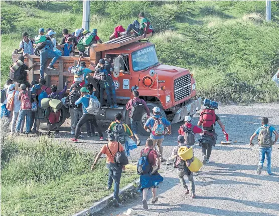  ?? GUILLERMO ARIAS/AFP ?? Migrantes de la caravana de hondureños rumbo a Estados Unidos trepan a un camión en Oaxaca, México