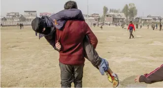  ?? — AP ?? KASHMIR: A Kashmiri man carries a wounded protester after he was hit by a tear gas shell during the funeral of Qaiser Sofi in Srinagar, Indian controlled Kashmir.