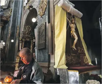  ?? CAROLYN COLE, LOS ANGELES TIMES ?? A wrap is lowered to cover the crucifix in case of a bombing at this church in Lviv, Ukraine, when church is in not in session.