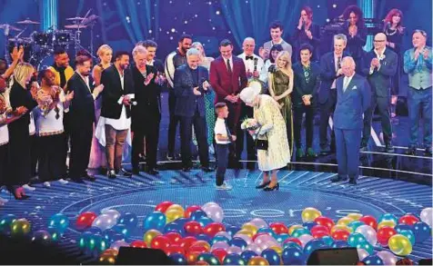  ?? AP ?? Queen Elizabeth II is presented with flowers by a young boy on stage at the Royal Albert Hall in London during a star-studded concert to celebrate the Queen’s 92nd birthday.