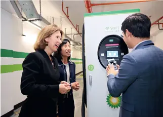  ??  ?? The ambassador learning how to pay for the charging of a new-energy vehicle by scanning a QR code.