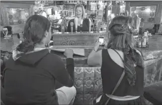  ??  ?? Fado Irish Pub worker Laura Lee Muchmore serves customers Luis Herrera and Chelsea Steele on a recent Warehouse Wednesday. The weekly event aims to draw customers back to the district’s bars and eateries.