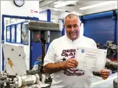  ?? VINCENT OSUNA PHOTO ?? Central Union High School’s Automotive Technology Instructor Ron Shane poses on Wednesday inside CUHS’s auto shop classroom with a Certificat­e of Excellence that was recently awarded to the school’s auto shop program. Central Union High has been the...