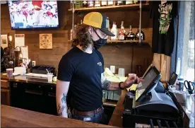  ??  ?? Bartender Jack Seale at the register at Beer Wall on Penn in West Reading Thursday afternoon.