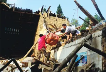  ??  ?? People remove their belongings at a collapsed house after a rainstorm in Lianyuan, Hunan province. — Reuters photo