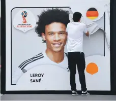  ?? AFP ?? A football museum employee in Dortmund removes Leroy Sane’s poster after he failed to make the final Germany squad