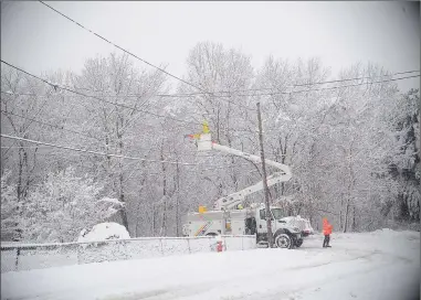  ?? Photo by Ernest A. Brown ?? National Grid technician­s work to restore power along Mayboro Street at Connecticu­t Avenue in Blackstone Friday afternoon. Heavy, wet snowfall brought down numerous trees and power lines in the area.