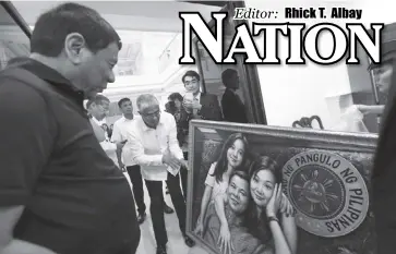  ?? PCOO ?? President Roderigo Duterte (leftmost) admires the family portrait gifted by Chinese Ambassador Zhao Jianhua after their meeting at the Presidenti­al Guest House in Davao City on Monday.