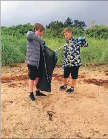  ??  ?? Archie Adams and Filip Dybalski collect rubbish discarded and washed up on Lamlash beach.