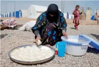  ?? Reuters ?? A displaced woman who fled the Daesh stronghold of Mosul makes bread with her children at the Khazer camp.—