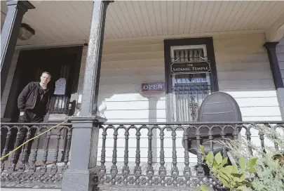  ?? AP FILE PHOTO ?? `WELCOMING': Satanic Temple co-founder Lucien Greaves on the porch of his group's Salem headquarte­rs, which will reopen Monday and feature an 8-foot statue of the satanic figure Baphomet.