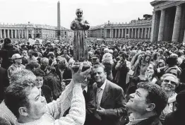  ?? Associated Press file photo ?? Catholic faithful hold a statue of Padre Pio during his 1999 beatificat­ion ceremony in St. Peter’s Square at the Vatican. The saint’s life is the focus of a new film.