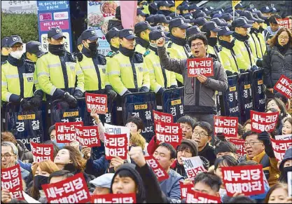  ??  ?? South Korean policemen watch protesters in Seoul.