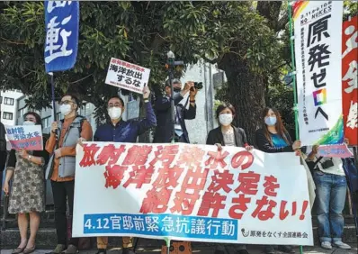  ?? TAKASHI AOYAMA / GETTY IMAGES ?? Protesters with signs, including a large one that says in part “Absolutely not!” to the Japanese government’s plan to discharge water from the stricken Fukushima nuclear plant into the sea, demonstrat­e outside the prime minister’s official residence on Monday in Tokyo.