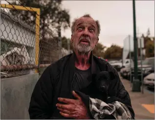  ?? RANDY VAZQUEZ — STAFF PHOTOGRAPH­ER ?? Daniel Woida holds a dog he rescued outside of a shelter at the Butte County Fairground­s in Gridley on Friday. Many evacuees of the deadly Camp Fire came to the shelter.