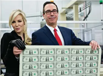  ??  ?? Treasury Secretary Steven Mnuchin and his wife, Louise Linton, holding an uncut sheet of one-dollar bills bearing Mnuchin’s name, Washington, D.C., November 2017