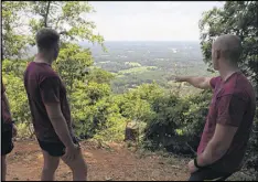  ??  ?? Adam Bannister (right) points to the North Georgia countrysid­e while talking to Dave Nichols after running up the hill World War II soldiers once trained on at Camp Toccoa at Currahee. Both men are members of the British 23 Parachute Engineer Regiment.