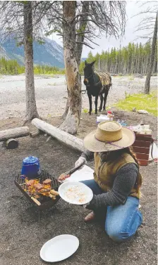  ?? GREG OLSEN ?? Wrangler Katie cooks steaks for lunch over an open fire.